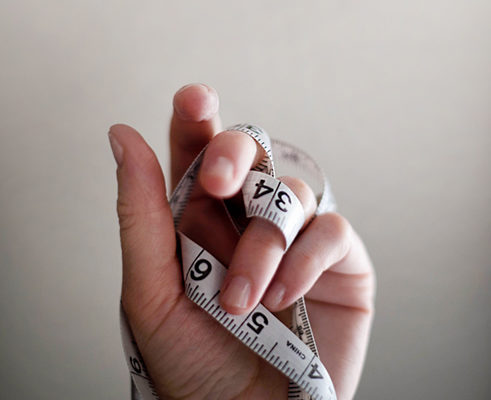 A photo of a hand holding measuring tape.